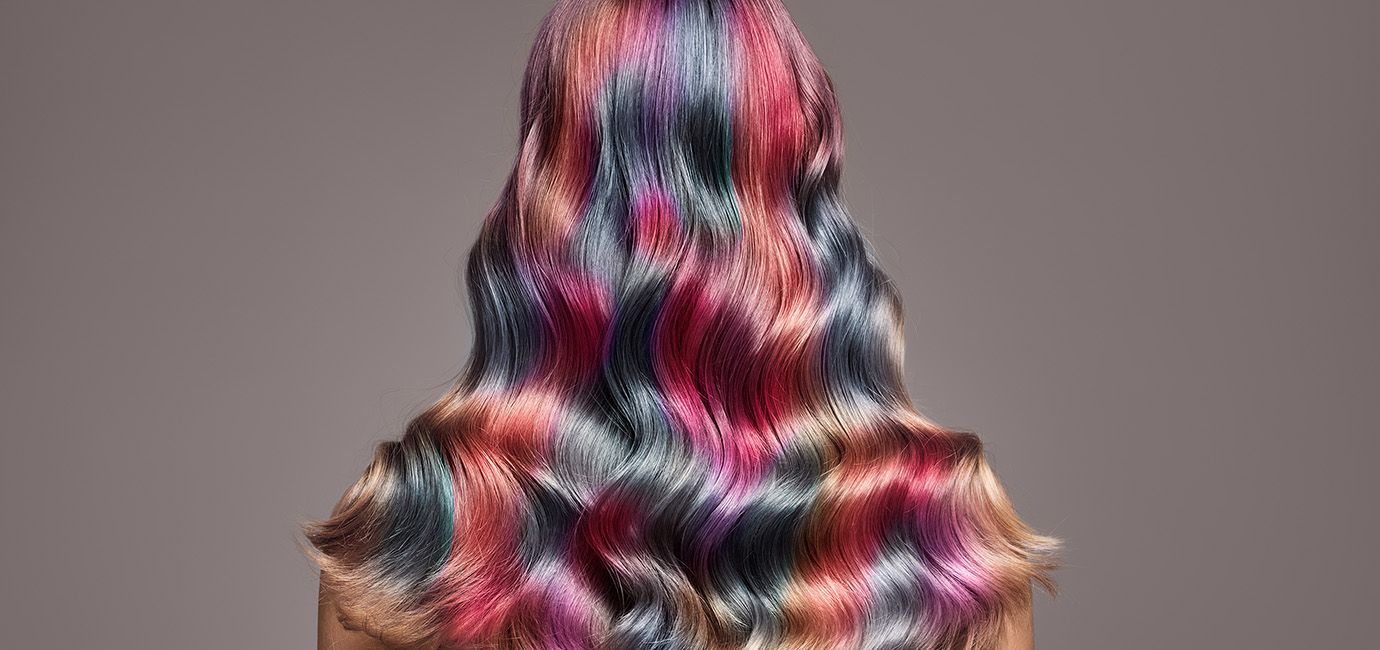 Image from the back of older female with wavy coloured hair.