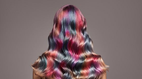 Image from the back of older female with wavy coloured hair.