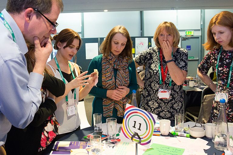 Group of business people looking at a table discussing issues as part of a workshop