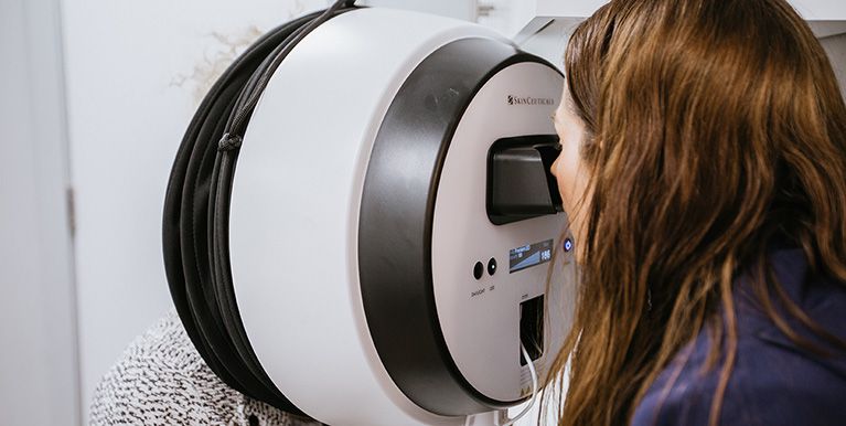 Female looking into a scanner to look in depth at a customer’s skin